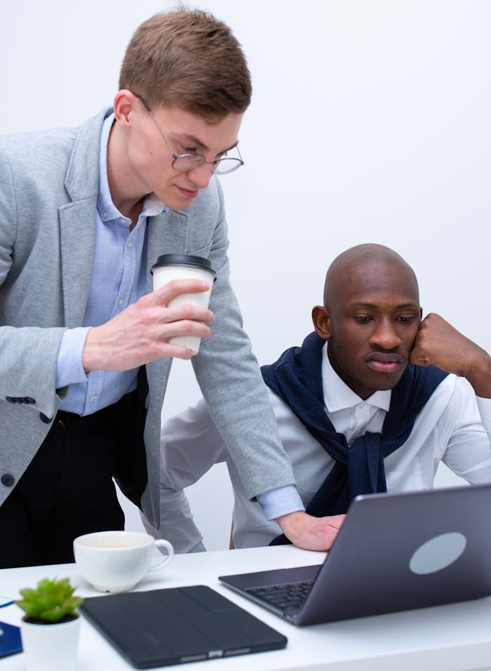 Two coworkers collaborating over a laptop in a bright office space.